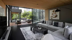 A modern minimalist living room with a large sofa, marble coffee tables, and a view of the garden through large windows.