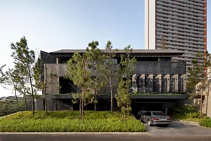 A modern residential home featuring black metal facade and greenery on the rooftop.