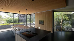 Modern residential kitchen featuring black wooden countertops and large glass windows.