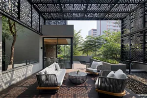 Modern urban living space featuring metal pergola, concrete walls, and wooden furniture.