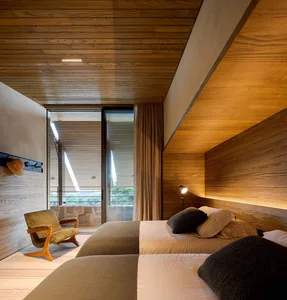 A minimalist bedroom featuring wooden walls and a cozy bed setup.