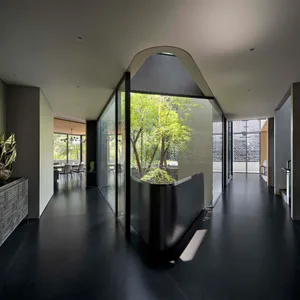 現代建築室內空間，玻璃牆面眺望寧靜花園景觀，採用光滑玻璃與混凝土材質