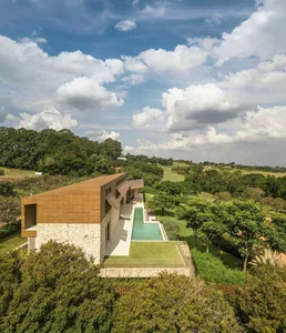 Modern residential house with wood and stone exterior, featuring a swimming pool and greenery.