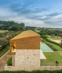 A modern residential outdoor space featuring stone and wood materials and a pool with a view of greenery.