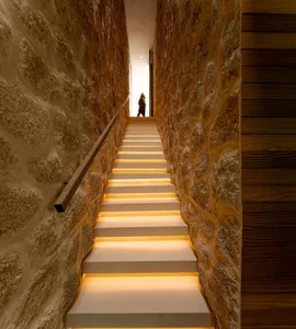 A modern staircase with illuminated steps and concrete walls.