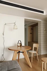 A minimalist dining room with wooden furniture, including a round table and chairs.