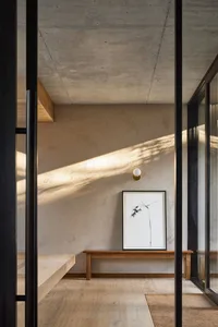 A minimalist interior space featuring concrete walls and wooden furniture.