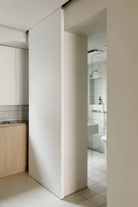 Modern bathroom with white and beige tiled walls, wooden vanity, and sliding door.