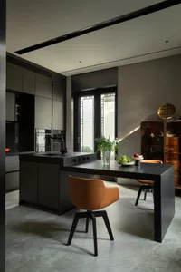 Modern kitchen with black stainless steel appliances and counters, featuring a island with an integrated sink and seating.