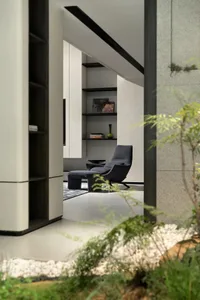 Modern living room with concrete walls and floor, featuring minimalist furniture and greenery.