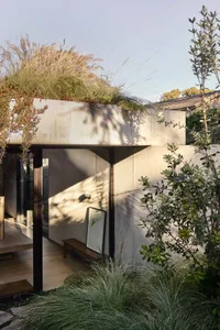Modern house with a concrete exterior featuring a green roof and garden.