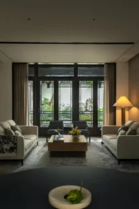 A modern living room featuring white sofas, dark wood coffee table, and floor lamp with yellow light.