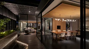 A modern living room with wooden floor and glass walls, featuring a contemporary black and white sofa and a sleek wooden coff