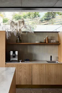 Modern minimalist kitchen with wooden cabinets, a concrete countertop, and a coffee machine.