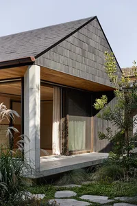 A modern residential house featuring wooden shingles and concrete.