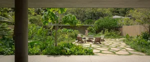 Outdoor garden with organic stone pathway, wooden benches, green plants, and a natural grassy area