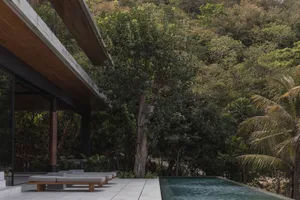 A modern house featuring concrete and glass materials surrounded by a natural setting.