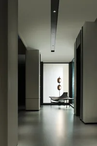 Modern lounge area with concrete walls and floor, featuring a unique seating arrangement and decorative lighting.