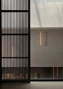 A minimalist interior with concrete walls and a large window with vertical slats.