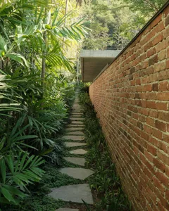 A pathway made of stone surrounded by lush greenery and a brick wall.