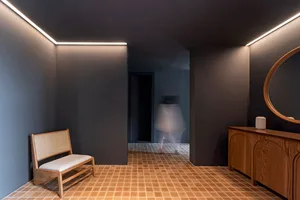 An entrance hall with minimalist design, featuring brick tiles on the floor and wooden furniture.
