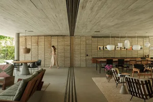 A modern interior design featuring wooden furniture, concrete elements, and lush plants.