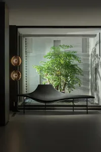 A sleek, minimalist leather sofa with an abstract, flowing shape, positioned against a backdrop of concrete walls in a contem