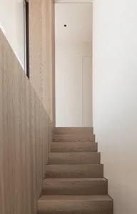 Modern minimalist staircase with wooden steps and light-colored walls.