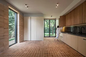 A modern residential kitchen features tile flooring and wood cabinets.