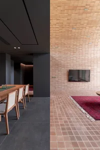 A modern living room with brick tiles on the walls and floor, featuring a wooden armchair and a red rug.