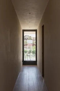 Modern minimalist residential hallway with wooden flooring and large window overlooking a garden.