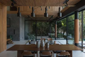 Modern architectural space featuring wooden elements and large glass windows overlooking a natural setting.