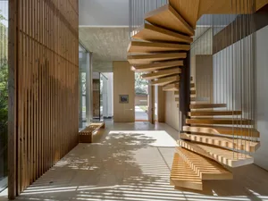 A modern floating staircase with wooden steps and cables hanging from the ceiling.