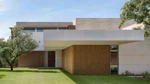 A modern residential building with a minimalist design, featuring concrete and wood materials.