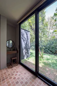 A modern interior with large windows overlooking a garden with concrete, tile, and wood elements.