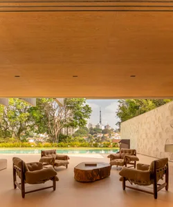 Modern minimalist living room with a wood floor and a large glass wall overlooking a pool and cityscape.