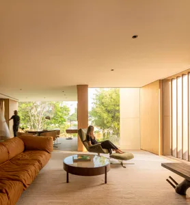 A spacious modern living room with wood furniture and a large window overlooking greenery.
