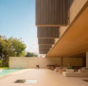 Modern residential living area featuring concrete, wood, and stone materials, with a pool and outdoor seating area.