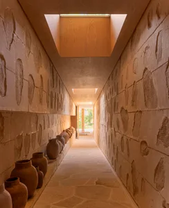 A hallway lined with clay vases, featuring a skylight.