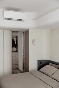Modern minimalist bedroom featuring minimalist furniture, wood finishes, and fabric bedding in neutral colors.
