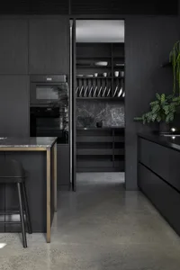 A modern, minimalist kitchen featuring dark wood cabinets, marble countertops, and concrete flooring.