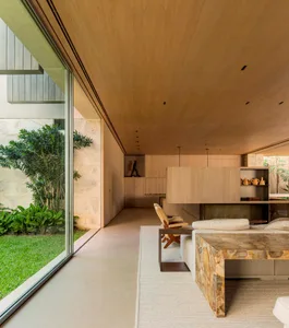 Modern minimalist living room featuring wooden walls, stone furniture, and a large glass window with greenery outside.