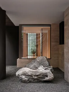Spacious minimalist living room featuring granite flooring, glass brick accent wall, and stone elements.