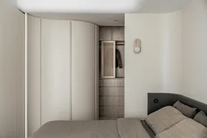 Modern, minimalist bedroom featuring neutral tones and a single bed.