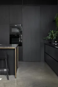 A modern kitchen with black wooden cabinets and a marble countertop.