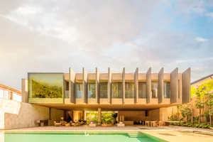 Modern building with sandstone exterior, large windows, and a swimming pool.