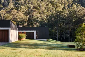 Modern home exterior with concrete and wooden features surrounded by greenery.