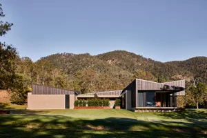 A modern house exterior featuring a combination of wood, cement, and concrete materials.
