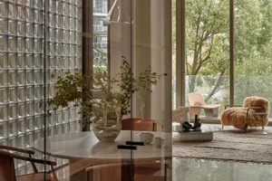 Modern living room with glass walls, marble flooring, and contemporary furniture.
