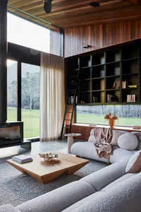 A modern living room with large windows, a wooden coffee table, and a comfortable sofa.